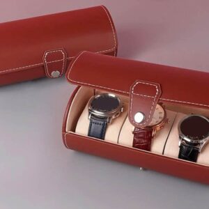 The Watch Travel Roll Case Brown Three spaces, featuring white stitching, securely holds three wristwatches on separate cushions. A second closed case sits beside it on a grey and mauve surface.