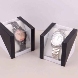 Two metal wristwatches, one black and one silver, are shown in separate Watch Storage Box Two Tone gift boxes with clear plastic lids, placed on a light-coloured surface against a plain background.