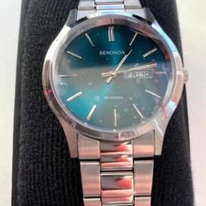 A Sekonda Men’s Watch 1826 with stainless steel bracelet and aqua blue dial, featuring day and date display, silver hour markers and hands, 50m water resistance, comes brand new in original packaging with black padded box.