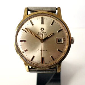 The Omega Genève Gold Plated Automatic 1970/71 features a gold case, silver dial with baton markers, date window at 3 o'clock, and black hour and minute hands.