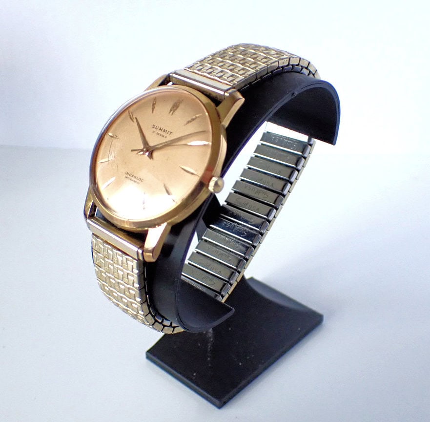 Stainless steel and gold vintage watch with a minimalist dial on display stand.