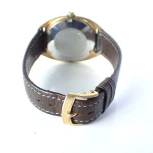 Vintage men's wristwatch with leather strap and gold-tone case, view from the back.