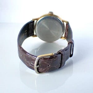 Vintage wristwatch with brown leather strap and gold case, showing the watch face from the back.