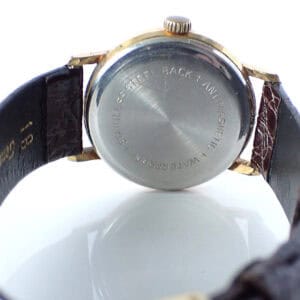 Stainless steel back of vintage watch with leather strap, close-up view.