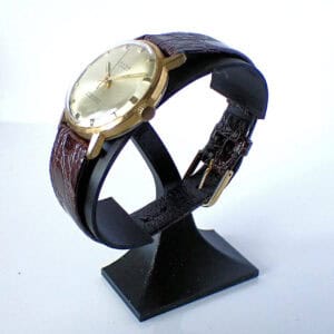Gold classic wristwatch with leather strap on display stand.