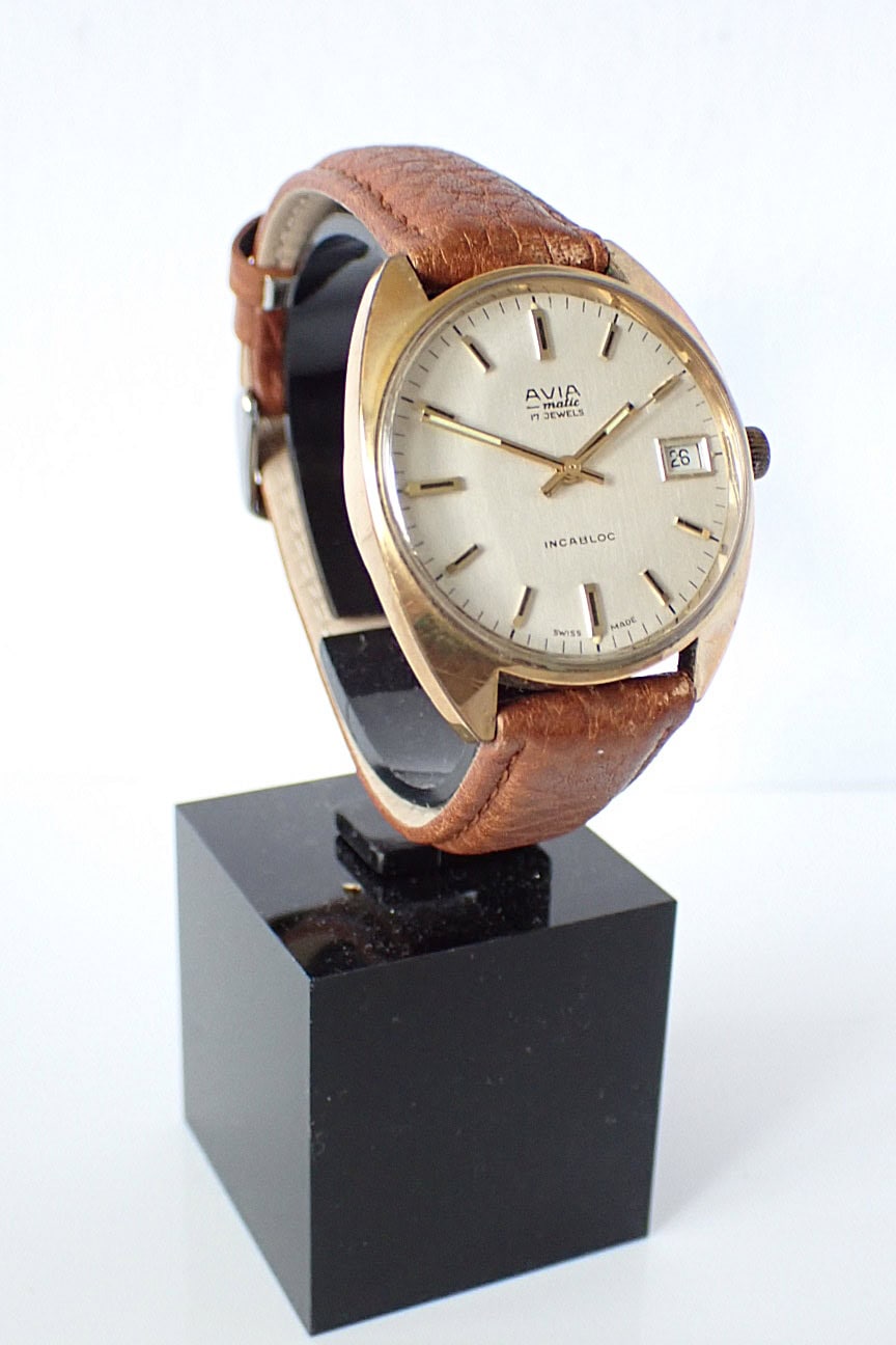 Vintage gold-tone wristwatch with cream dial and brown leather strap, Swiss made, classic automatic timepiece.