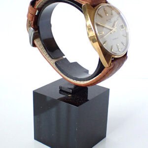 Vintage gold-tone wristwatch with a brown leather strap on display.
