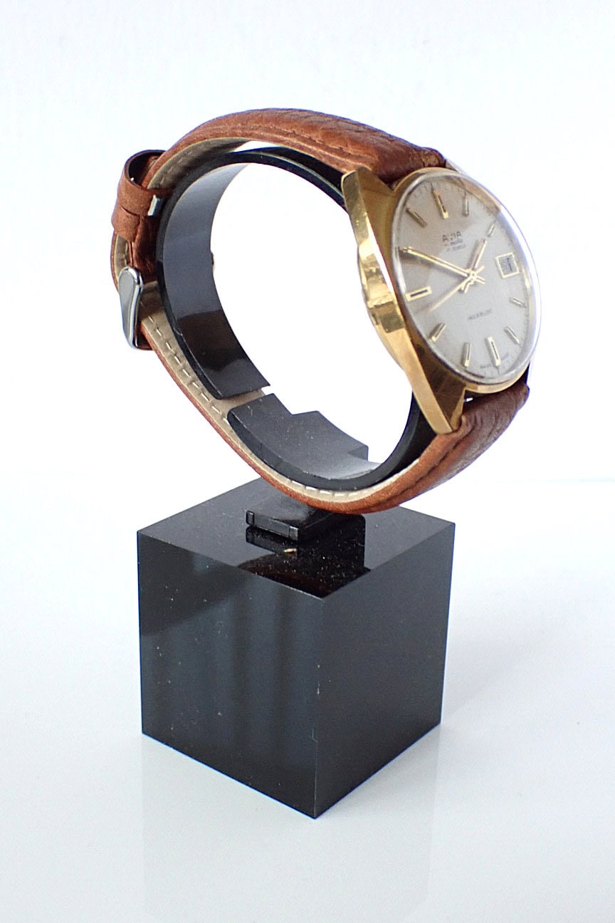 Vintage gold-tone wristwatch with a brown leather strap on display.