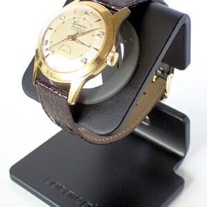 Elegant gold dress watch with leather strap on black watch stand for luxury timepieces.
