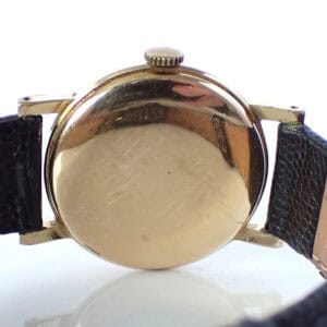 Vintage gold-tone wristwatch with black leather strap, minimalist design, classic men's timepiece.