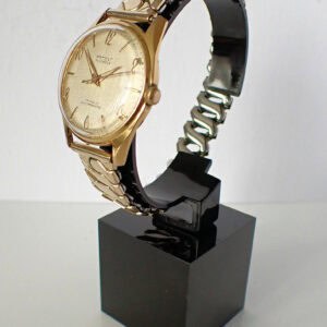 Golden vintage wristwatch with metal bracelet on display stand.