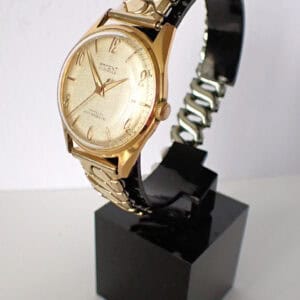 Gold vintage wristwatch with metal bracelet on display stand, classic men's timepiece.