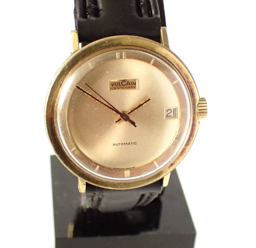 Vintage Vulcain Centenary automatic wristwatch with gold case and black leather strap.