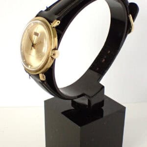 Vintage Vulcain gold-tone men's wristwatch with black leather strap on display stand, elegant luxury timepiece.