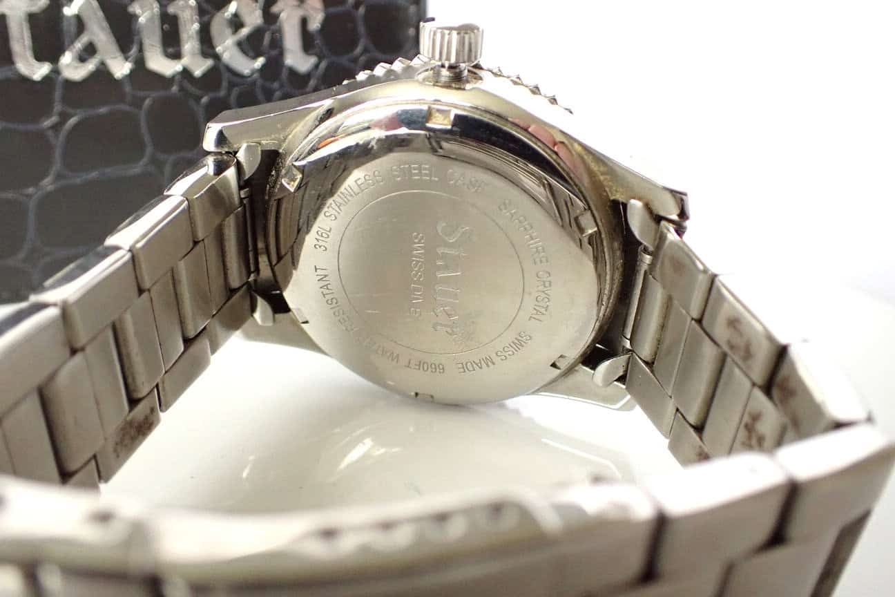 Stainless steel watch back with engraved details and metal link bracelet close-up.