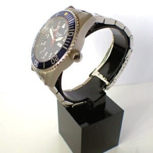 Men's diver watch with black bezel and stainless steel bracelet, displayed on black stand.