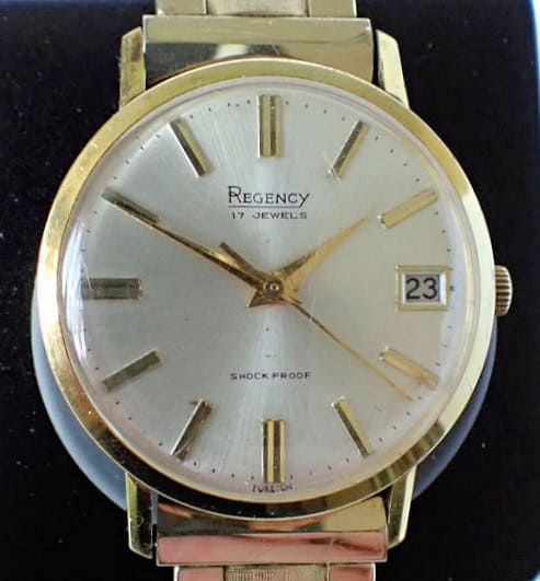 A Regency 17 Jewels 1970s Gold Plated Mechanical wristwatch with a silver dial, marked "17 Jewels" and "Shock Proof," shows the time as 10:08 with a date window set to 23.