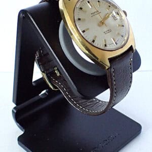 Gold vintage wristwatch with leather strap on display stand, classic luxury watch style.