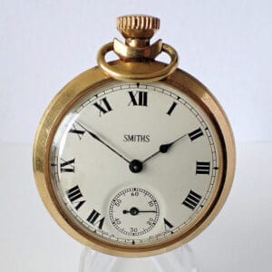 A Smiths Gold Tone Stem Wind Pocket Watch featuring black Roman numerals, a white dial, and a small seconds subsidiary dial at the bottom, set against a plain white background.