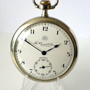 A Thomas Russell and Sons Premier Pocket Watch from the 1920s, featuring black numerals, hands, and a seconds sub-dial, is displayed on a clear stand against a white background.