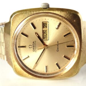 A vintage Omega Day Date Genève Automatic Watch c.1973 with a square gold case, metallic strap, and champagne dial displaying day and date in English. The hands show about 3:58.