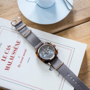 Elegant BRISTON chronograph watch with grey strap on a wooden table, stylish and luxury timepiece.