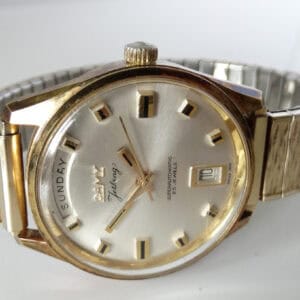 A vintage Camy Gold Plated Jetking Day-Date Automatic (Superautomatic) 1975 wristwatch with a metallic strap, silver dial, gold hour markers and hands, showing Sunday and date. Pay interest-free in three with Klarna.