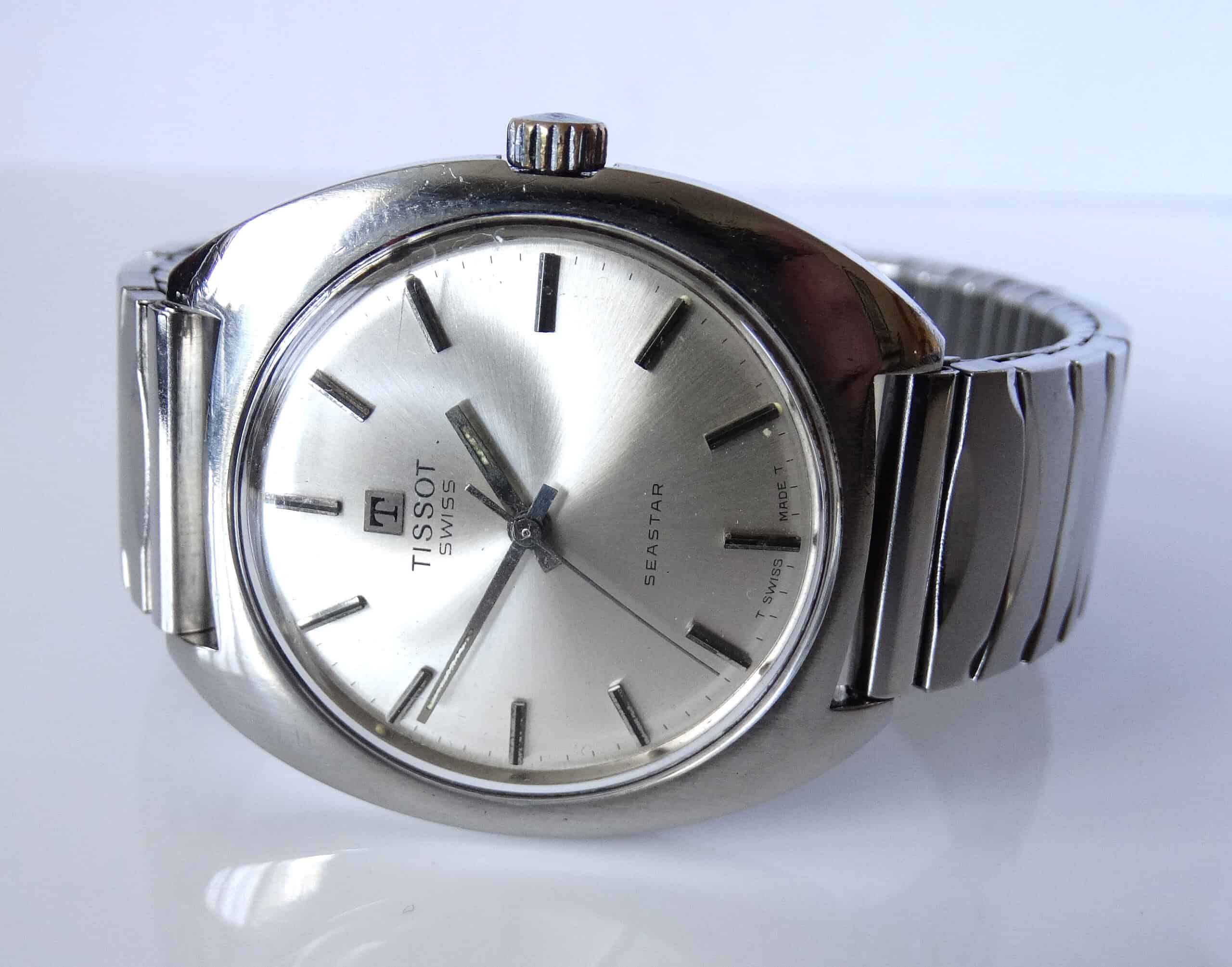 A Tissot Seastar Manual Wind Jumbo 1972 wristwatch with a round dial, silver hour markers, and matching metal strap is displayed on a white surface.