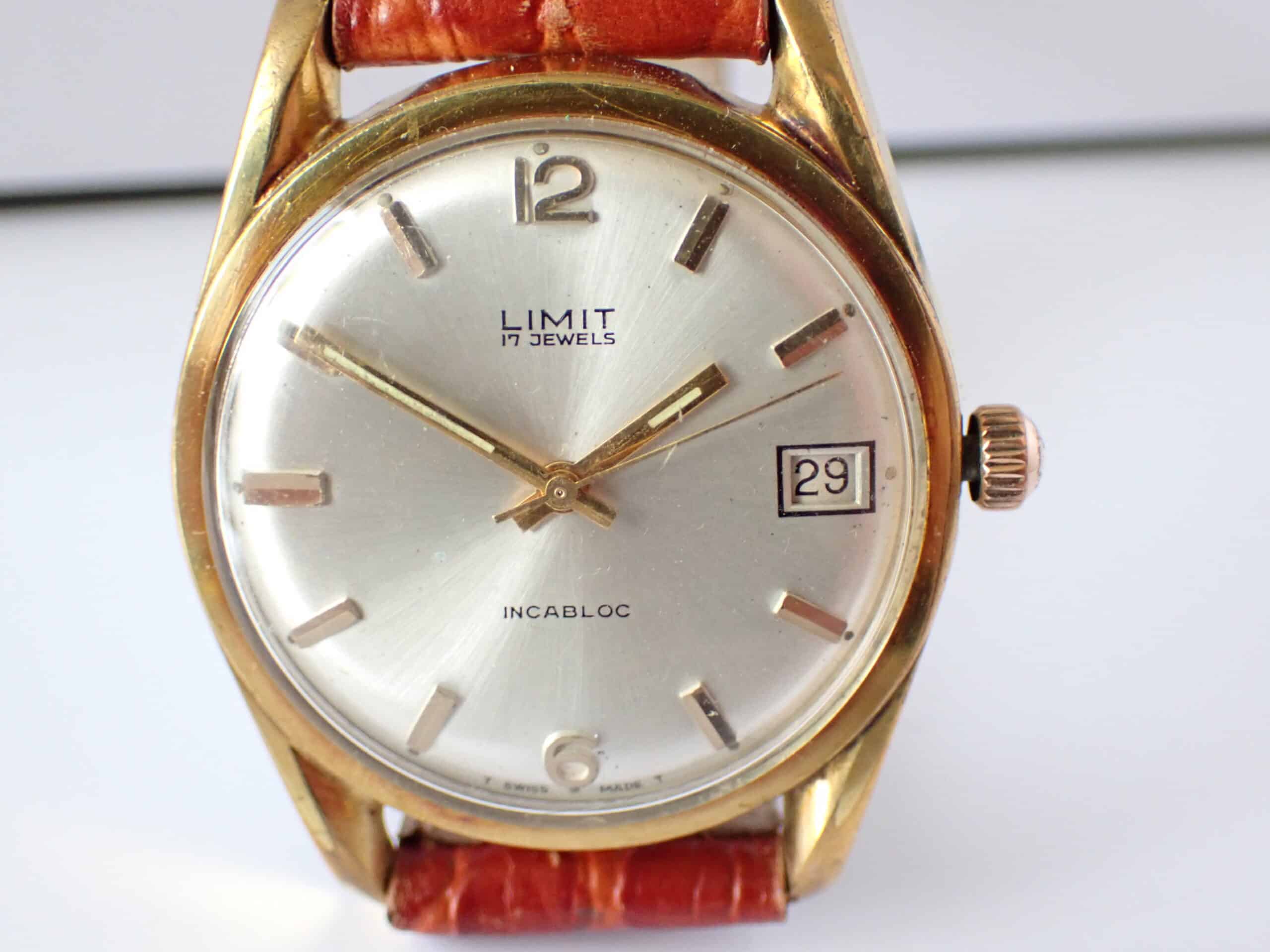 A vintage Limit 17 Jewels Date Mechanical Incabloc wristwatch with Swiss movement, gold case, white dial marked "LIMIT 17 JEWELS INCABLOC," gold hour markers, date window at 29, and brown leather strap.