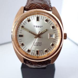 A Tissot 21 Jewel Automatic gold-plated cushion watch with a date window, silver dial, black markers, brown leather strap, and gold hands showing about 8:22:52. Pay with Klarna.