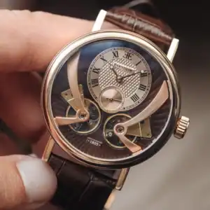 A close-up of a luxury wristwatch with a brown leather strap, Roman numerals, intricate exposed gears, and gold accents, held between a person’s thumb and finger.