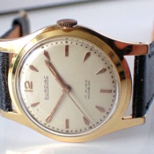 A rare Surdiac gold-plated Swiss mechanical watch with a cream dial, silver hour markers, and black leather strap. Dial reads 17 RUBIS INCABLOC; time shown is 11:09. Pay interest-free in three with Klarna.