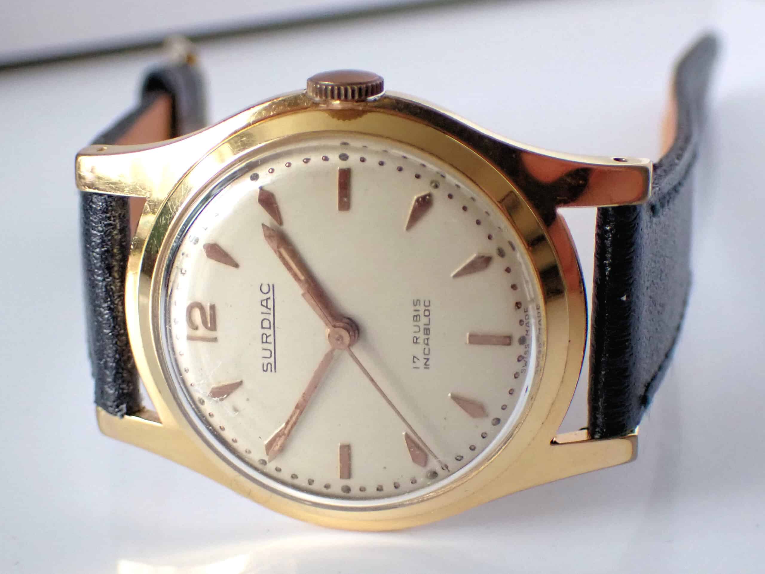 A rare Surdiac gold-plated Swiss mechanical watch with a cream dial, silver hour markers, and black leather strap. Dial reads 17 RUBIS INCABLOC; time shown is 11:09. Pay interest-free in three with Klarna.