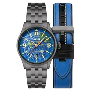 The AVI-8 FLYBOY Capcom 1942 Automatic Pixel Limited Edition Gunmetal Ace AV-4121-22 features a blue digital-patterned dial, yellow and green hands, stainless steel bracelet, date window, and is shown with a blue and black leather strap with white stitching.