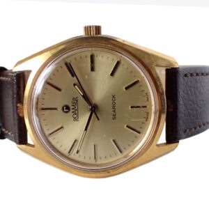 A 1972 Roamer SEAROCK Mechanical watch featuring a gold-toned round face, black hour markers, and brown leather strap. Minimalist design with ROAMER and SEAROCK on the dial. Pay interest-free in three with Klarna.