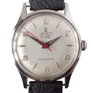 The Lanco De Lux 17 Jewel Mechanical Watch features a white dial, gold hour markers, black hands, a red second hand, and a black textured leather strap. The face reads “LANCO DE LUXE 17 JEWELS” and “SWISS MADE.” Pay interest-free in three with Klarna.