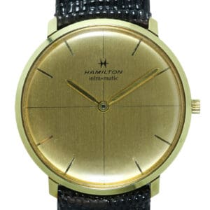 The Hamilton Intra Matic Automatic Watch features a gold case, minimalist design, thin black hour markers, gold hands, and a black textured leather strap. Pay interest-free in three with Klarna.