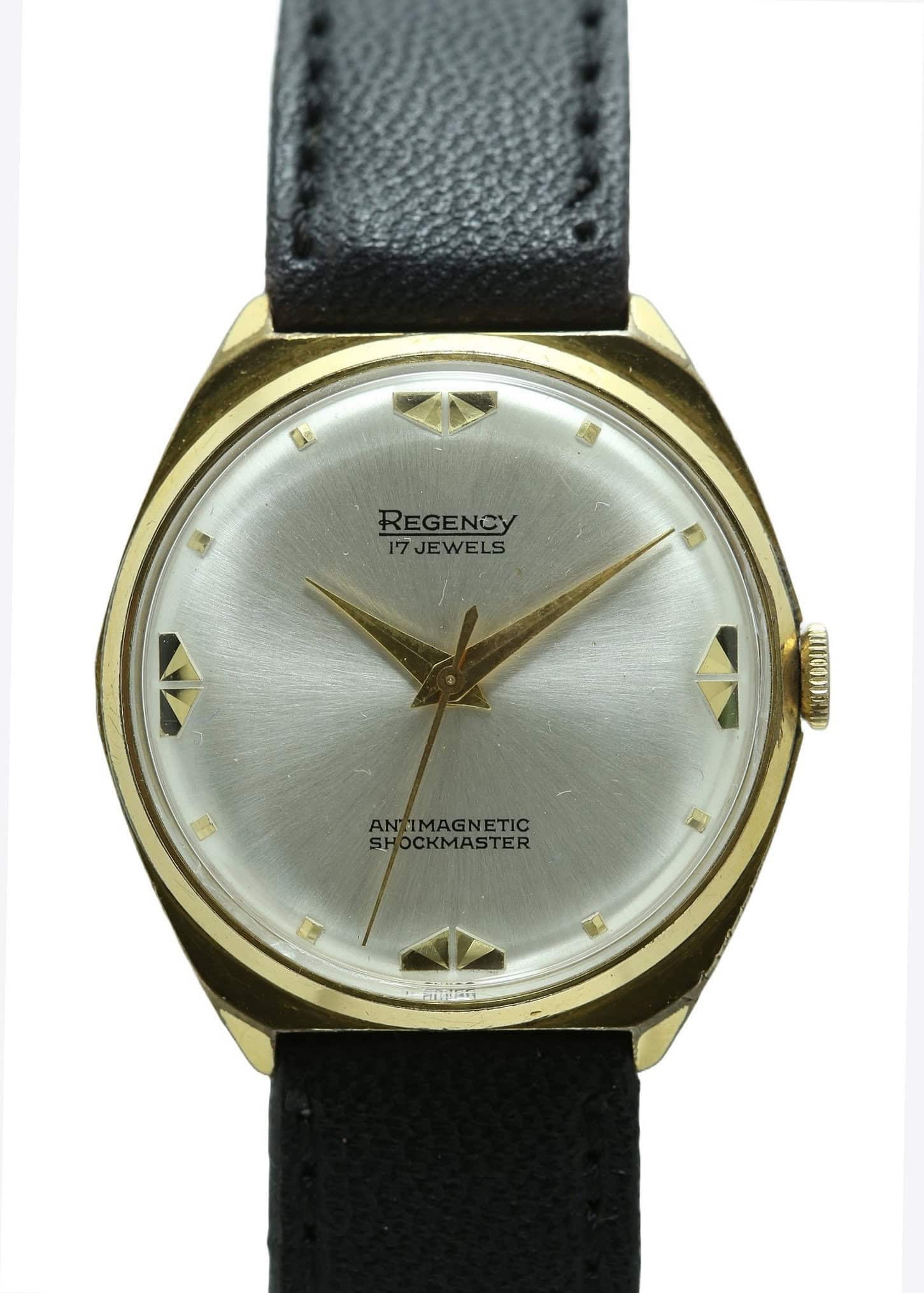 The Regency Deco Style Mechanical Watch features a gold-tone round case, silver dial with gold geometric hour markers, black hands, and a black leather strap. Dial reads "Regency 17 Jewels" and "Antimagnetic Shockmaster." Pay interest-free in three with Klarna.
