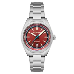 The James McCabe Scrambler Automatic Burnt Red features a stainless steel case, a burnt red dial, silver hour markers, and a date window at 6 o’clock. The background displays a blurred gradient of matching watch colours.