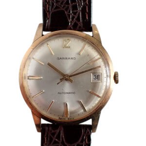 A vintage Garrard Automatic 9ct gold presentation watch (Chubb Safe and Lock Company, 1971) features a silver dial, gold markers, date window (31), and dark brown textured leather strap. Pay in 3, interest-free with Klarna.