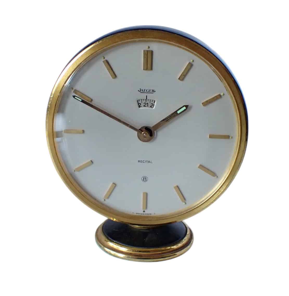 A Jaeger-LeCoultre 8-Day Table Clock, Recital Alarm with a 24-hour scale, features a white dial, gold accents, minimal markers, and is mounted on a small gold and black base. Pay later with Klarna.