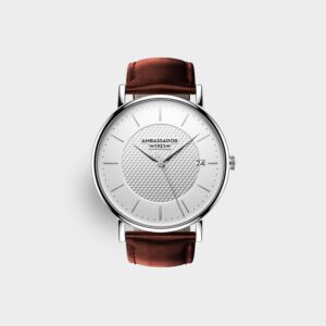 The Prime Ambassador Heritage 1921 is a minimalist analogue wristwatch with a white textured dial, silver hour markers, date at 3 o’clock, “AMBASSADOR 1921” branding, a brown leather strap, and silver case on a plain light background.