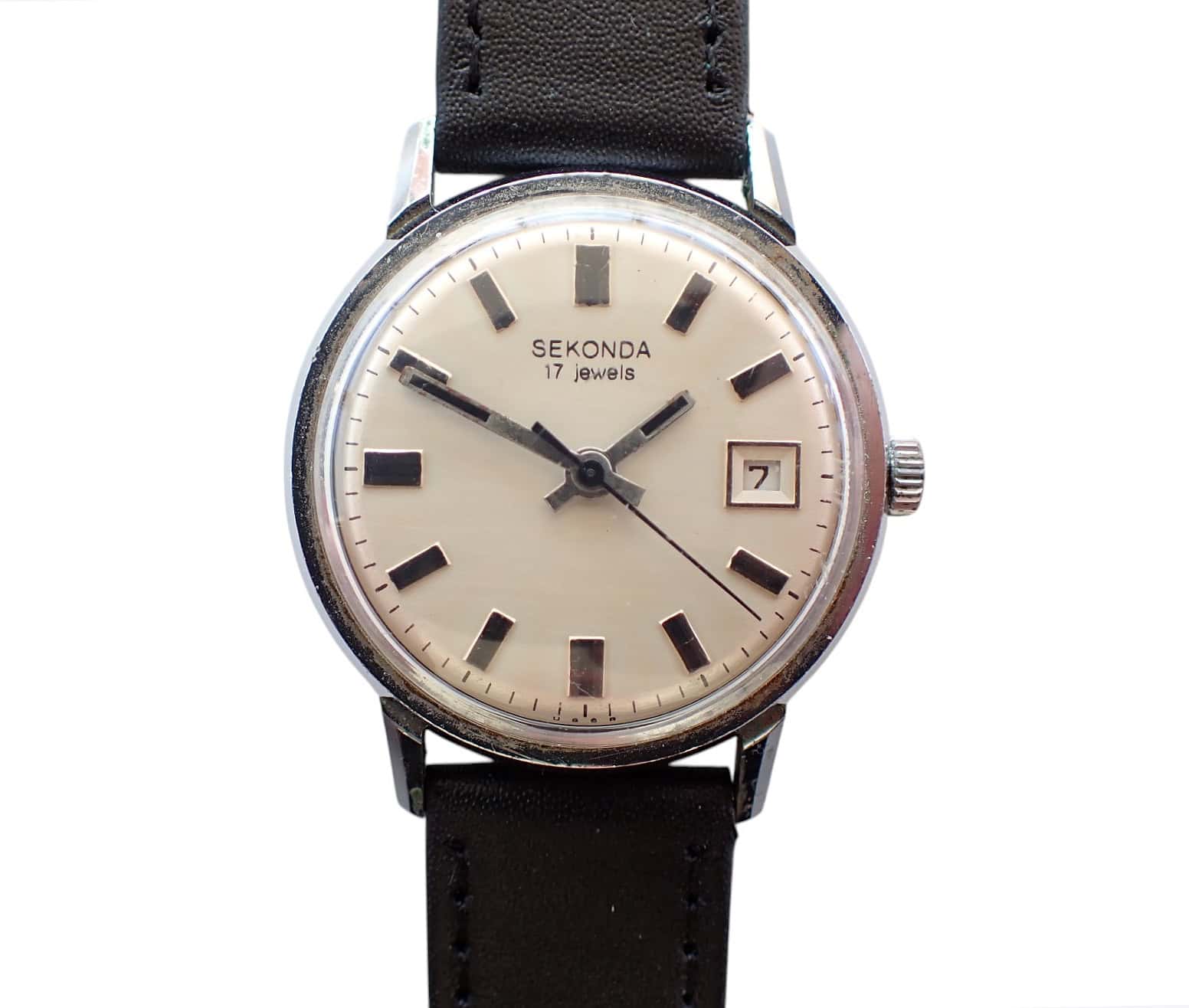 A vintage SEKONDA 2414 POLJOT 17 Jewels c.1970 wristwatch with a white dial, black hour markers, date window at 3 o'clock, and black leather strap. The hands show 10:10 and the face reads SEKONDA 17 jewels.