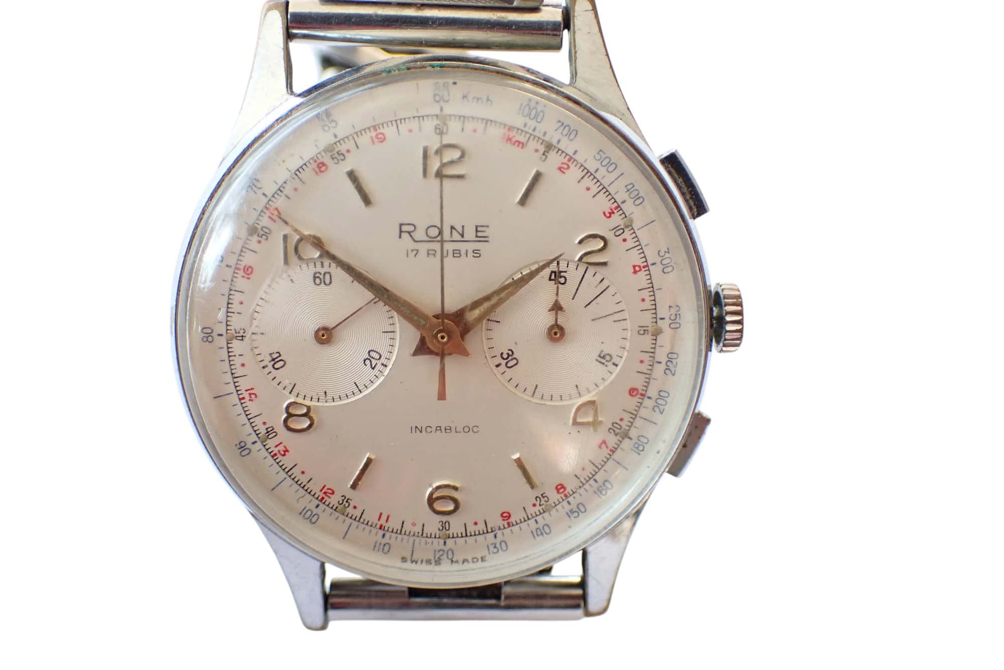A vintage Rone Chronograph wristwatch with a silver case, white dial, gold hands, two subdials, and black/red numerals. The time displayed is 2:18:32.