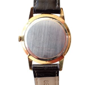 Stainless steel watch back with gold watch case and leather strap, classic vintage design.