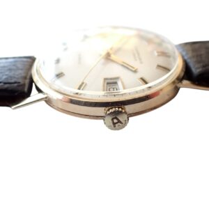 Vintage wristwatch with black leather strap and gold case, featuring date display and classic design.
