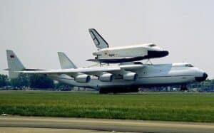 Giant aircraft with space shuttle model on top at an airfield, showcasing aviation technology.