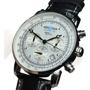 The Zeppelin Airship Commemorative Version Men's Watch 2025 features a white dial, black hands, three sub-dials, tachymeter scale, date window, and black leather strap with the brand logo and "100 Jahre" displayed on the face.