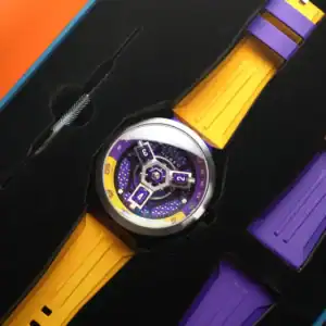 The NUBEO SKYLAB AUTOMATIC LIMITED EDITION Indigo NB-6083-0H features a modern geometric face with purple, yellow, and silver accents, a purple and yellow strap, black foam packaging, and includes an extra purple strap.