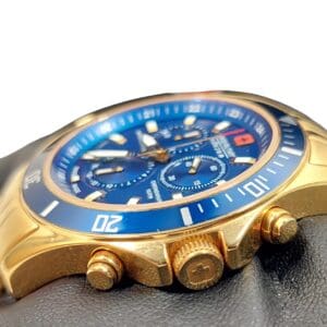 A close-up of the Swiss Military Hanowa Flagship Chrono Sapphire 06-4183.7/6-51837 gold wristwatch with a blue dial, three sub-dials, and a date window, displayed on a black gloved hand against a white background.